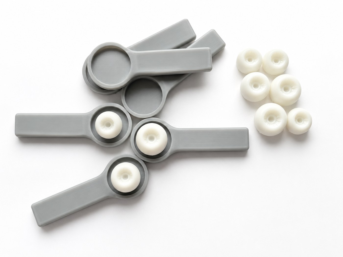 Mehrere graue Resin-Augenhalter und weiße Augen-Rohlinge nebeneinander ausgelegt.